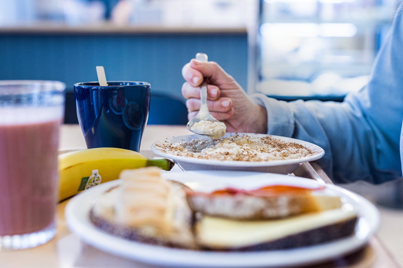 hand som håller i sked vid grötskål