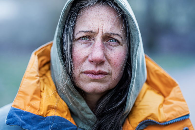 Kvinna med hoodie och jacka tittar rakt in i kameran